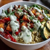 Golden roasted sweet potatoes, zucchini, and bell peppers top a warm bowl of Lentil Power Bowl with fluffy quinoa and creamy tahini dressing.