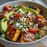 The finished Simple Grain Bowl shows diced cucumbers, carrots, and feta cheese on fluffy quinoa.
