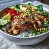 A finished Coconut Rice Peanut Bowl garnished with chopped peanuts and fresh lime wedges on the side.