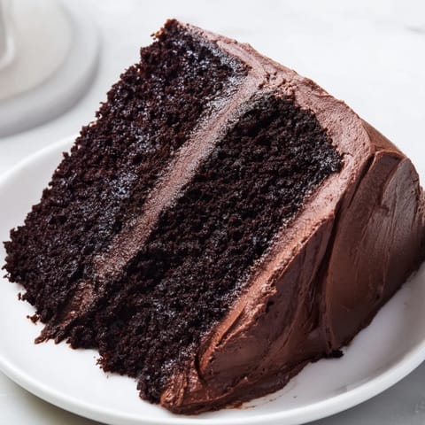 This moist Devil's Food Cake is shown sliced, revealing the dark chocolate interior, ready to serve.