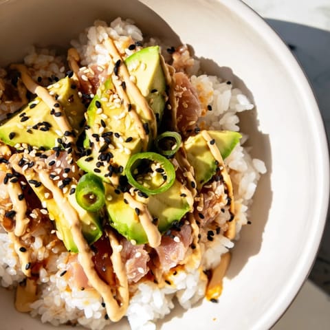 A vibrant Tuna Avocado Rice Bowl with flaky tuna, creamy avocado, crisp cucumber, and toasted sesame seeds on fluffy jasmine rice.