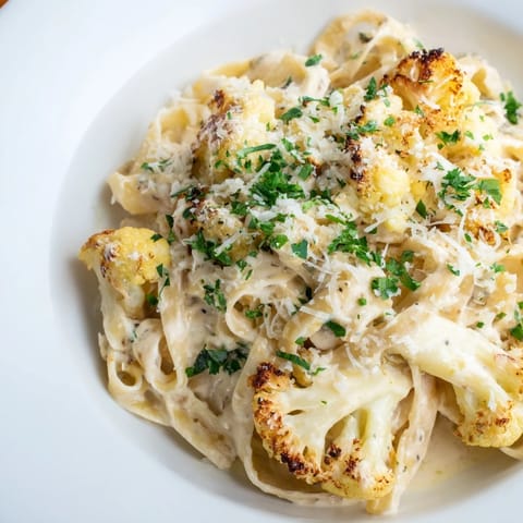 Roasted Cauliflower Alfredo pasta in a white bowl, creamy sauce clinging to noodles with a sprinkle of black pepper.