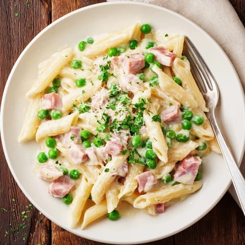 Creamy penne pasta tossed with sweet spring peas and savory diced ham, garnished with fresh parsley and Parmesan.  