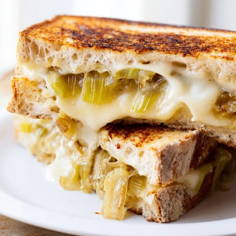 Golden slices of Havarti & Caramelized Leek Grilled Cheese ooze from buttery sourdough, served warm beside a fresh green salad.