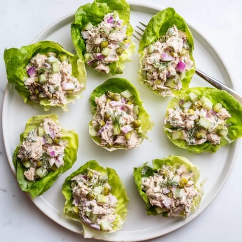 Crisp butter lettuce cups filled with creamy dill pickle chicken salad, garnished with fresh dill.