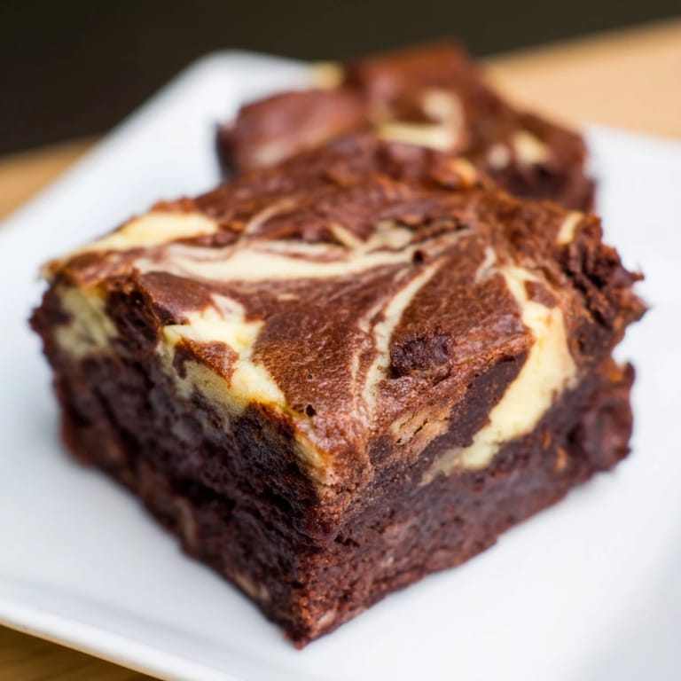 Perfectly baked cheesecake brownies, swirled to show a hint of creamy cheesecake goodness.