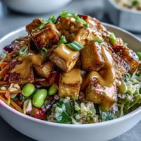 Golden brown tofu cubes and vibrant veggies over fluffy quinoa in a Peanut Tofu Power Bowl.
