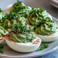 Green avocado deviled eggs with fresh herbs, perfect for spring parties and healthy snacking.  