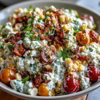 Creamy Corn Salad with Jalapeño in a white bowl, garnished with fresh cilantro and diced vegetables, served as a colorful summer side dish.